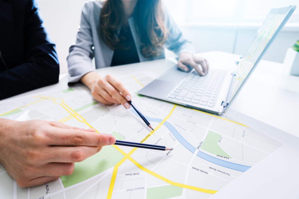 twopeoplelookingatcitymapwithlaptopattable