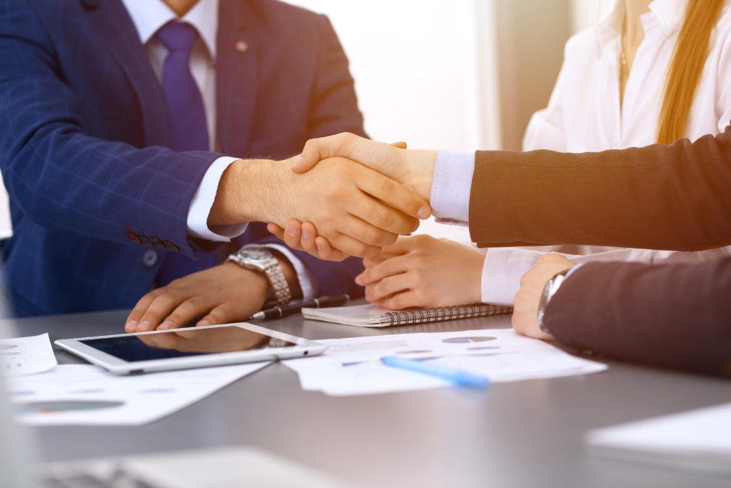 businesspeopleshakinghandsfinishingupapaperssigning-meeting