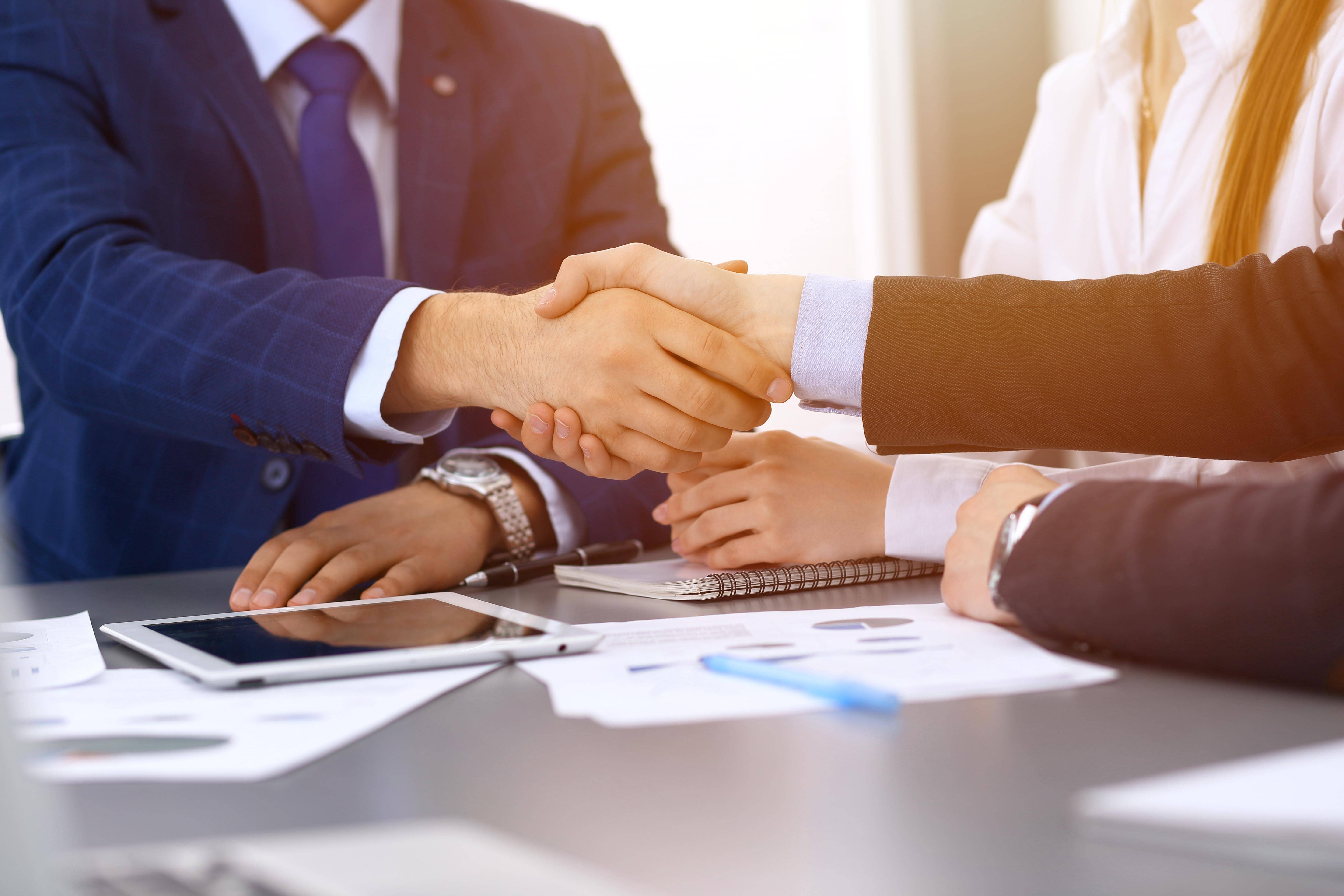 businesspeopleshakinghandsfinishingupapaperssigning-meeting