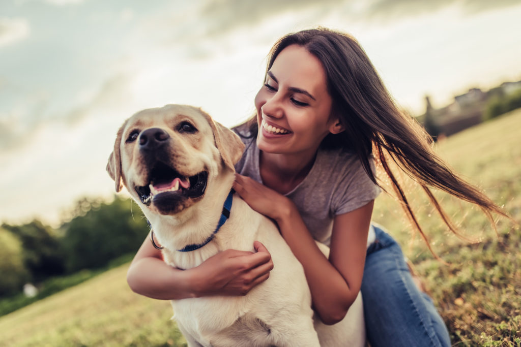 attractiveyoungwomanwithlabradoroutdoors-womanonagreen