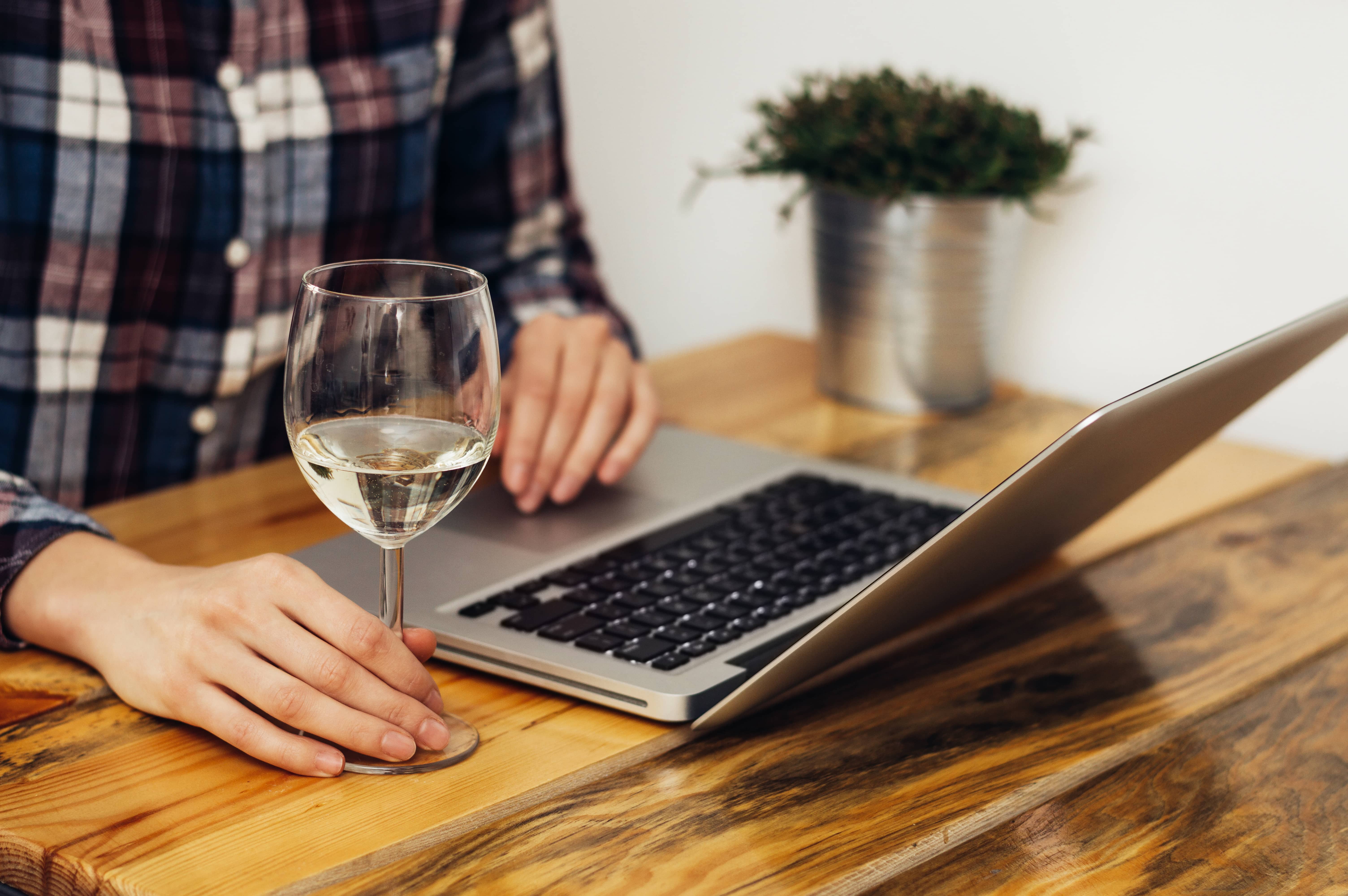 closeupofwomanhandswithglassofwineandcomputer