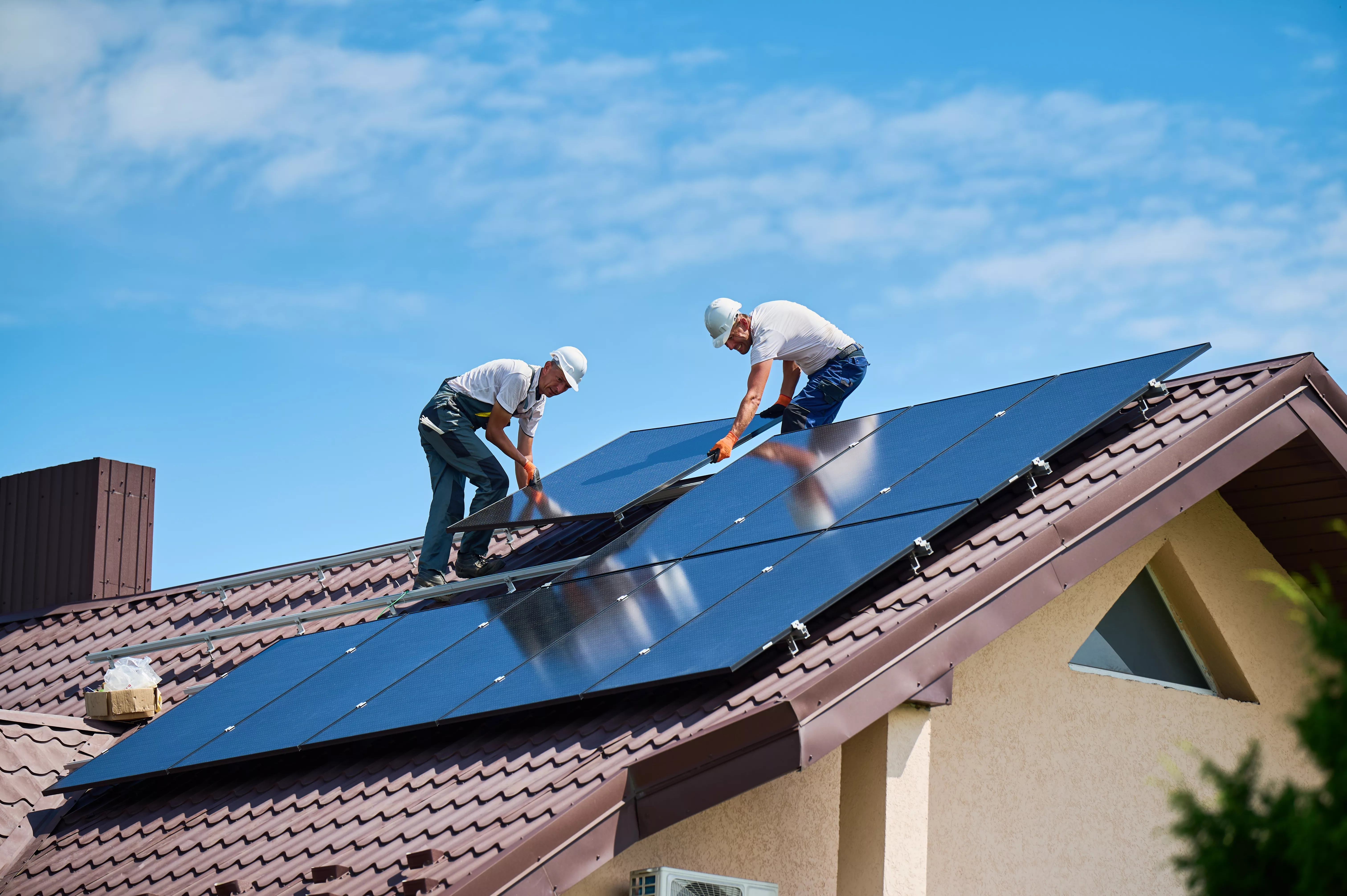 workersbuildingsolarpanelsystemonrooftopofhouse-two