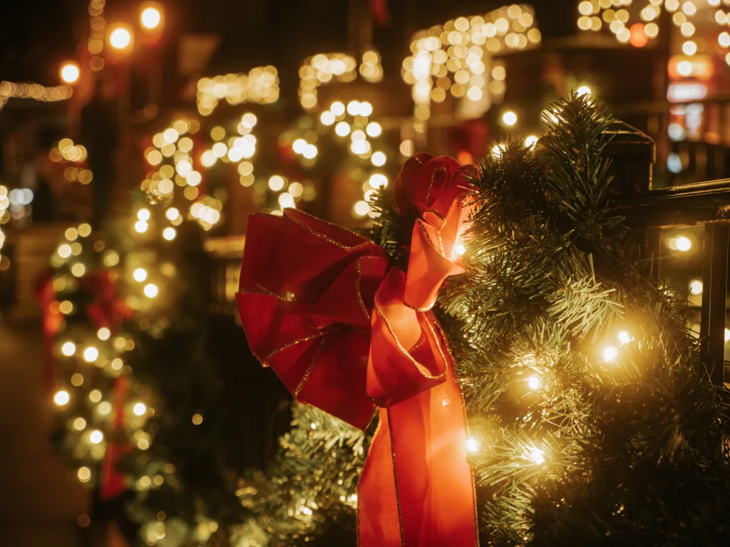 redholidaybowonhanginggarlandwrappedinchristmaslights