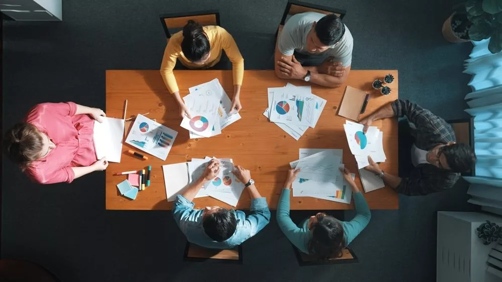 topdownviewofstartupbusinessteamholdingpaper