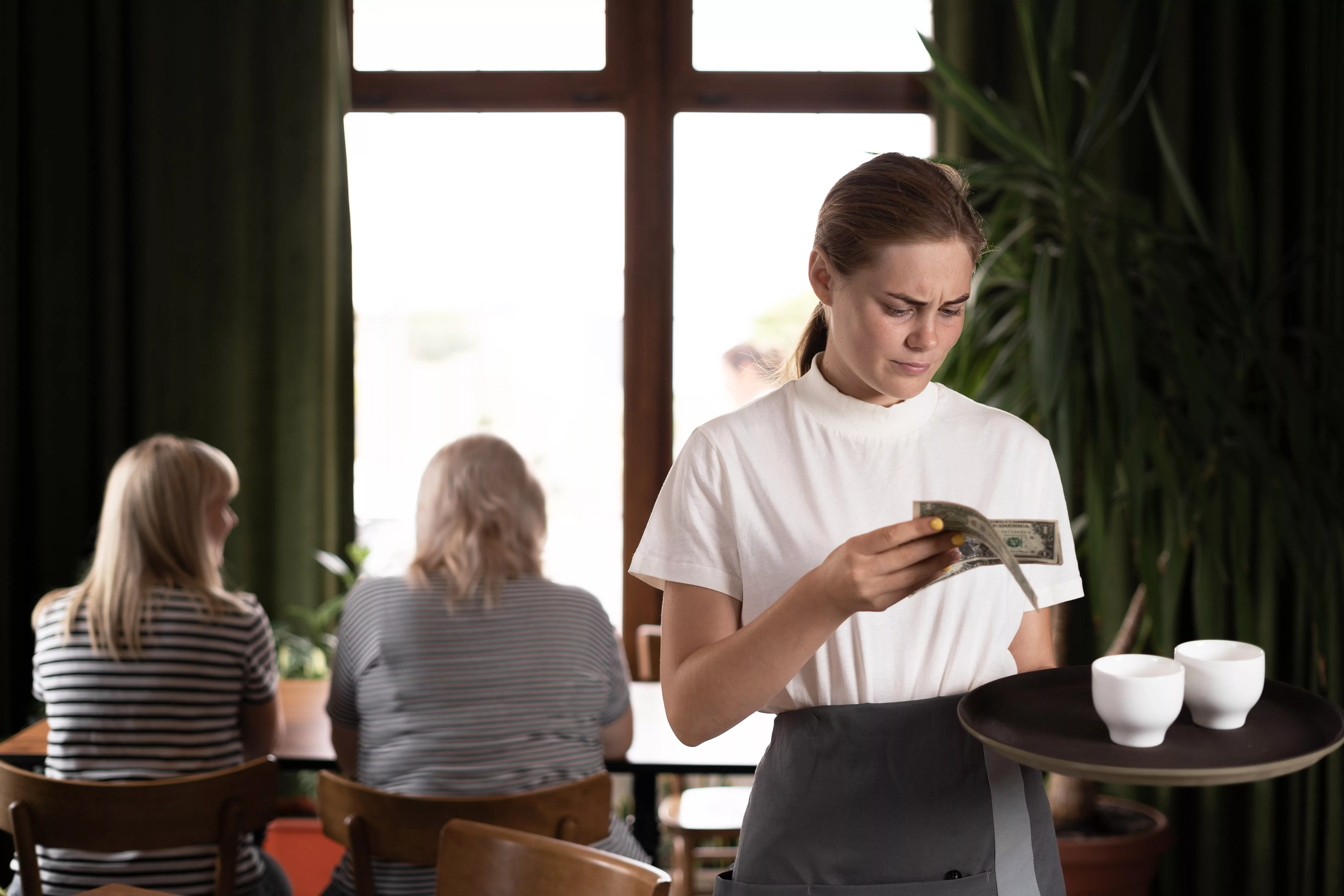 disgruntledfemalewaiterholdingservingtrayinrestaurantwithbad