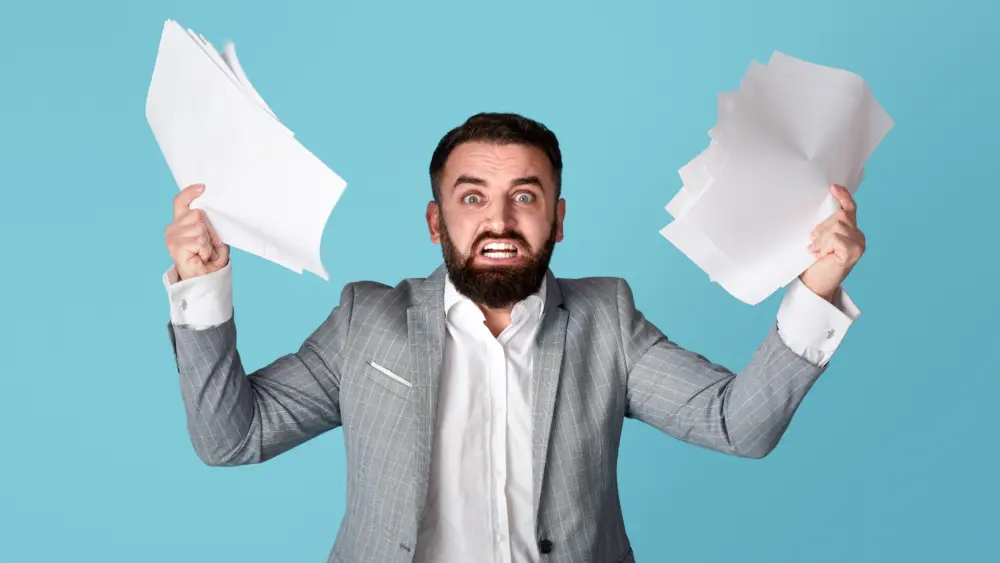 dealingwithworkplacestress-angryoverworkedofficeemployeegraspingpaper