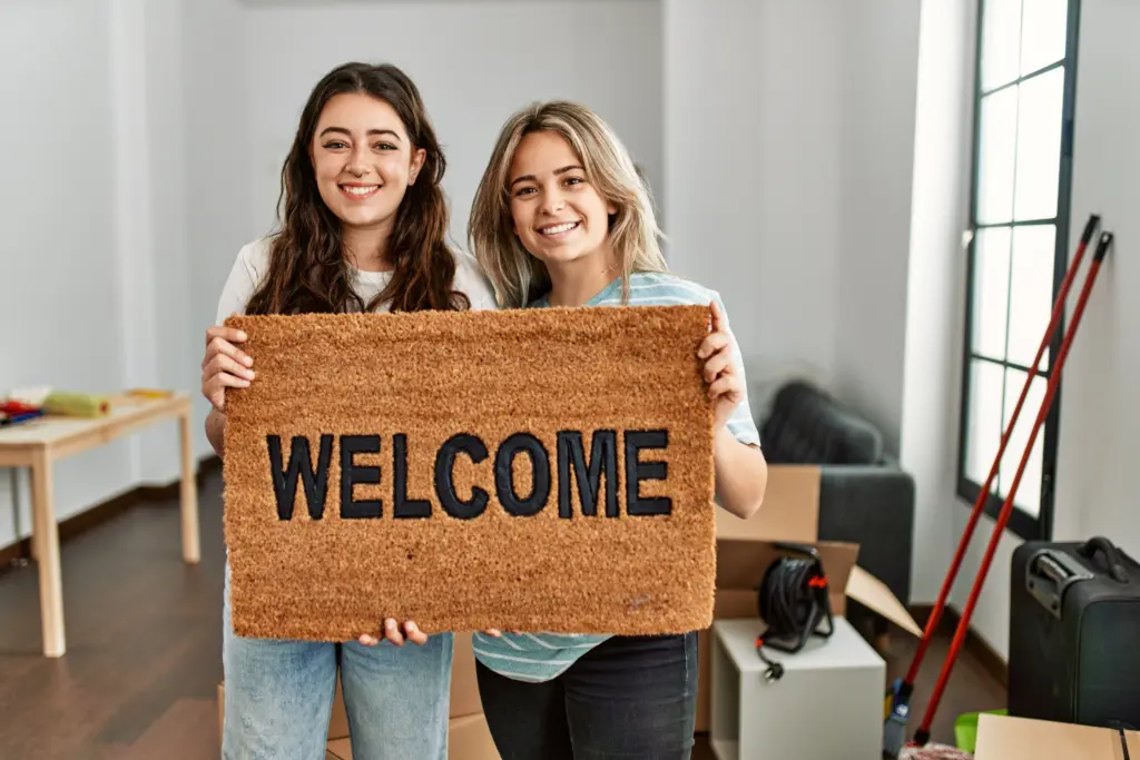 youngbeautifulcouplesmilinghappyholdingwelcomedoormatatnew