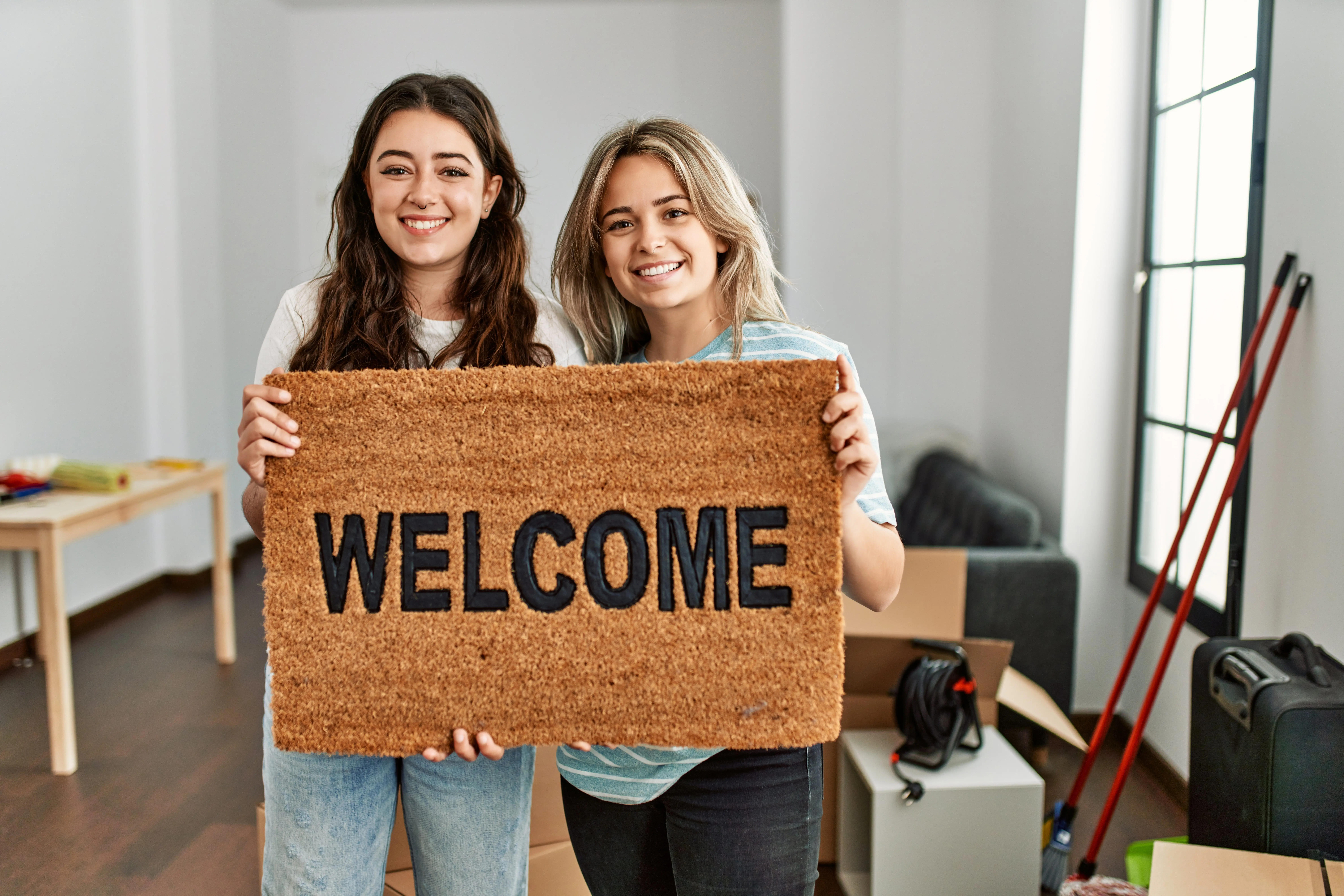 youngbeautifulcouplesmilinghappyholdingwelcomedoormatatnew