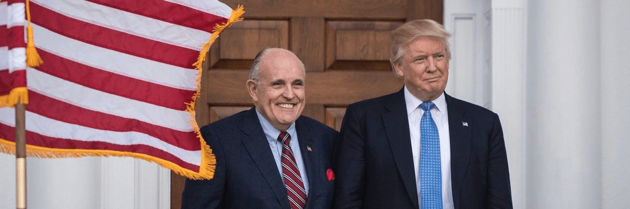 Rudy Giulinai and President Trump smiling by flag
