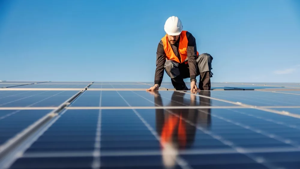 A worker installing solar panels on the roof