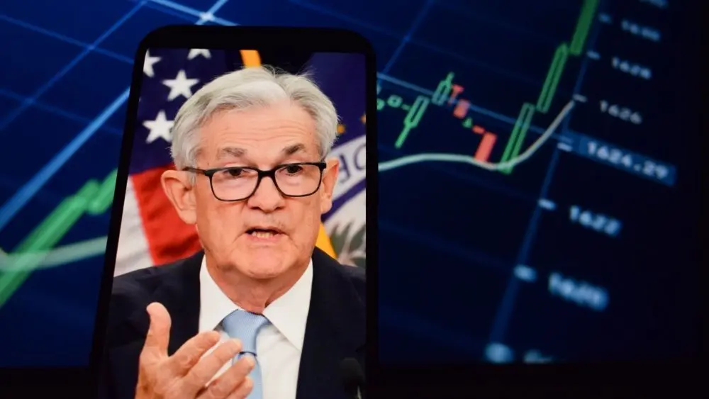 On the smartphone screen^ Federal Reserve (Fed) Chair Jerome Powell is visible. In the background^ an inflation rate chart is displayed. 19.04.2025. New York^ U.S