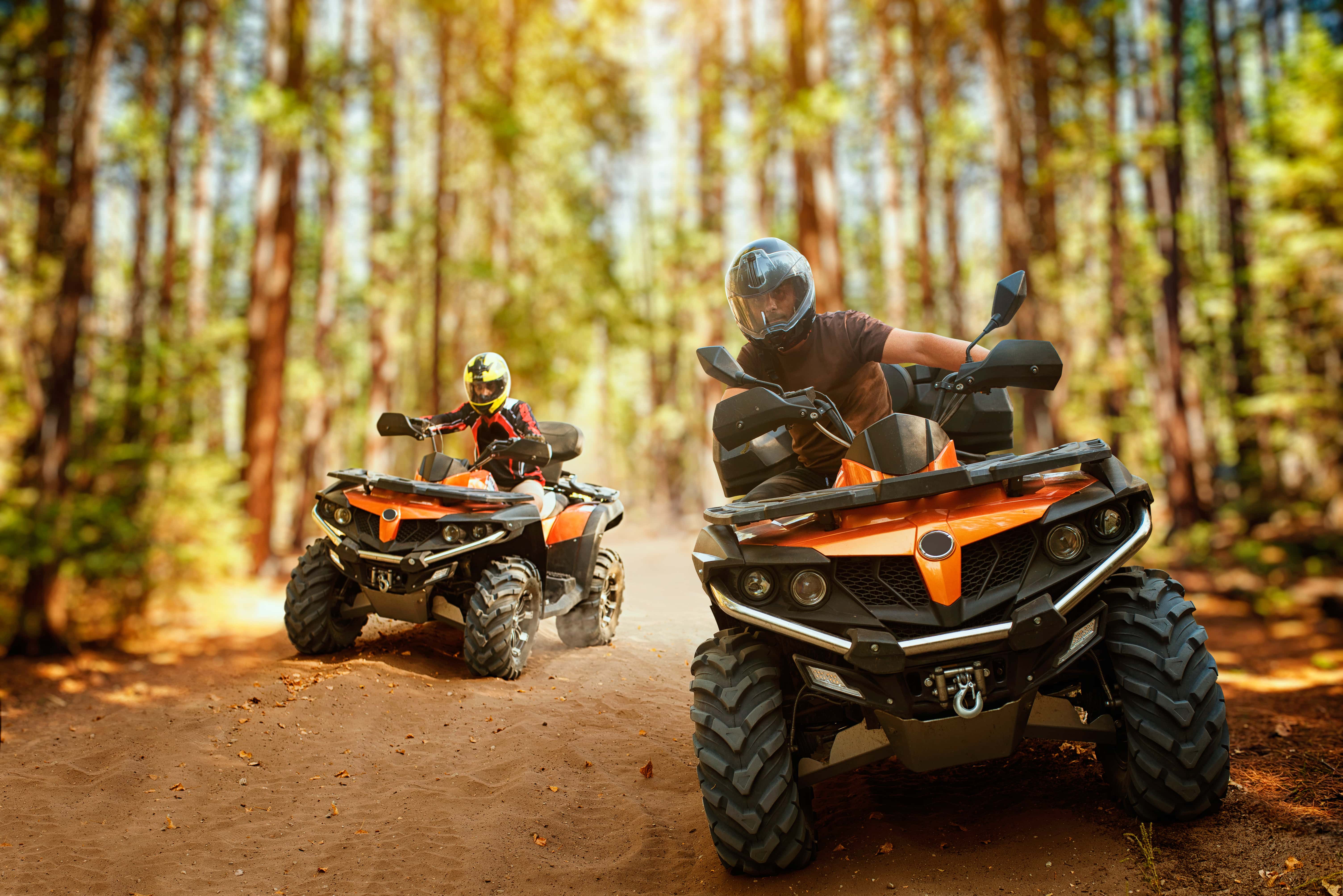 two-atv-riders-speed-race-in-forest-front-view