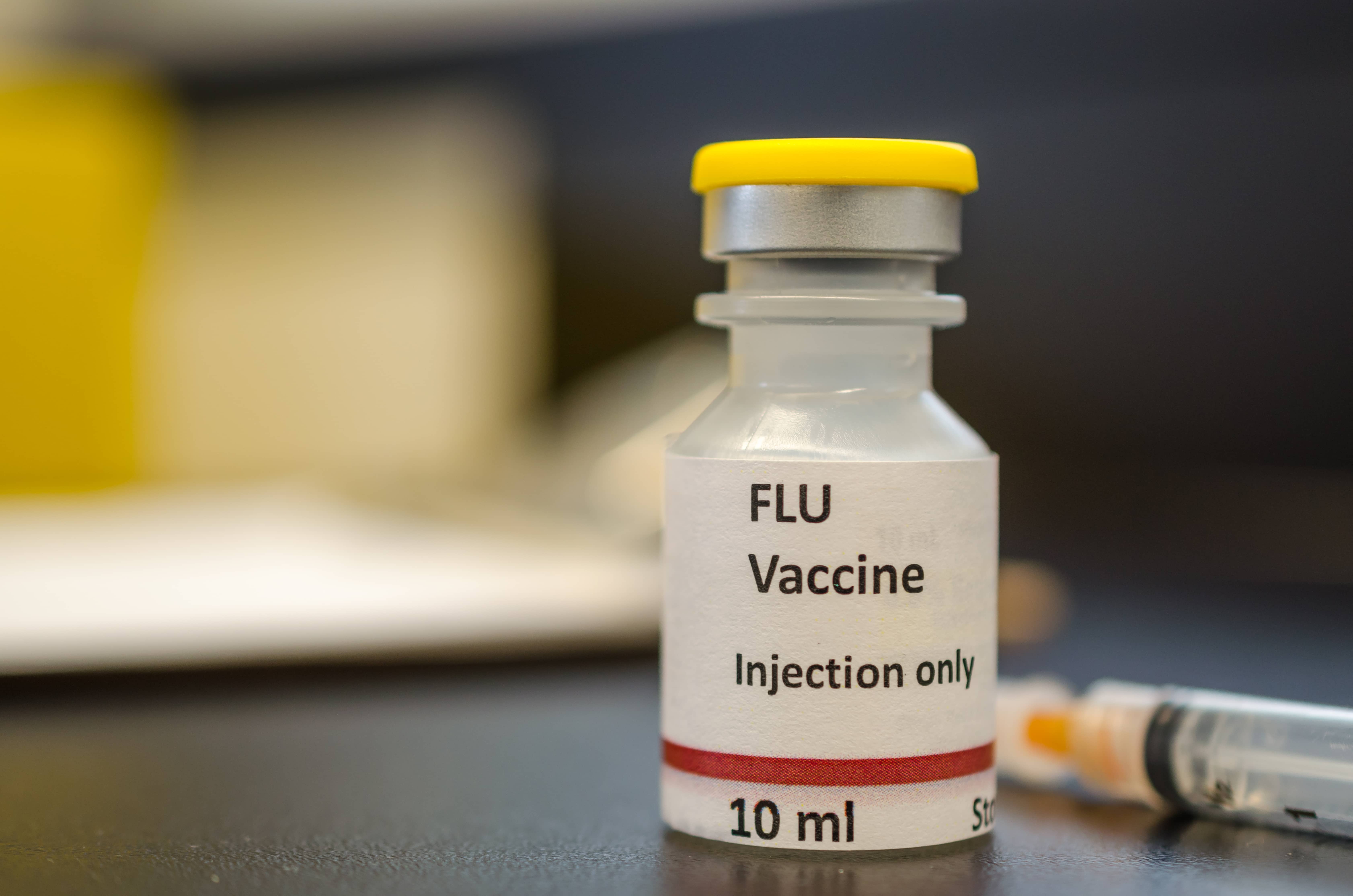 a-vial-of-flu-vaccine-with-a-syringe-at-the-backgr-587cscx