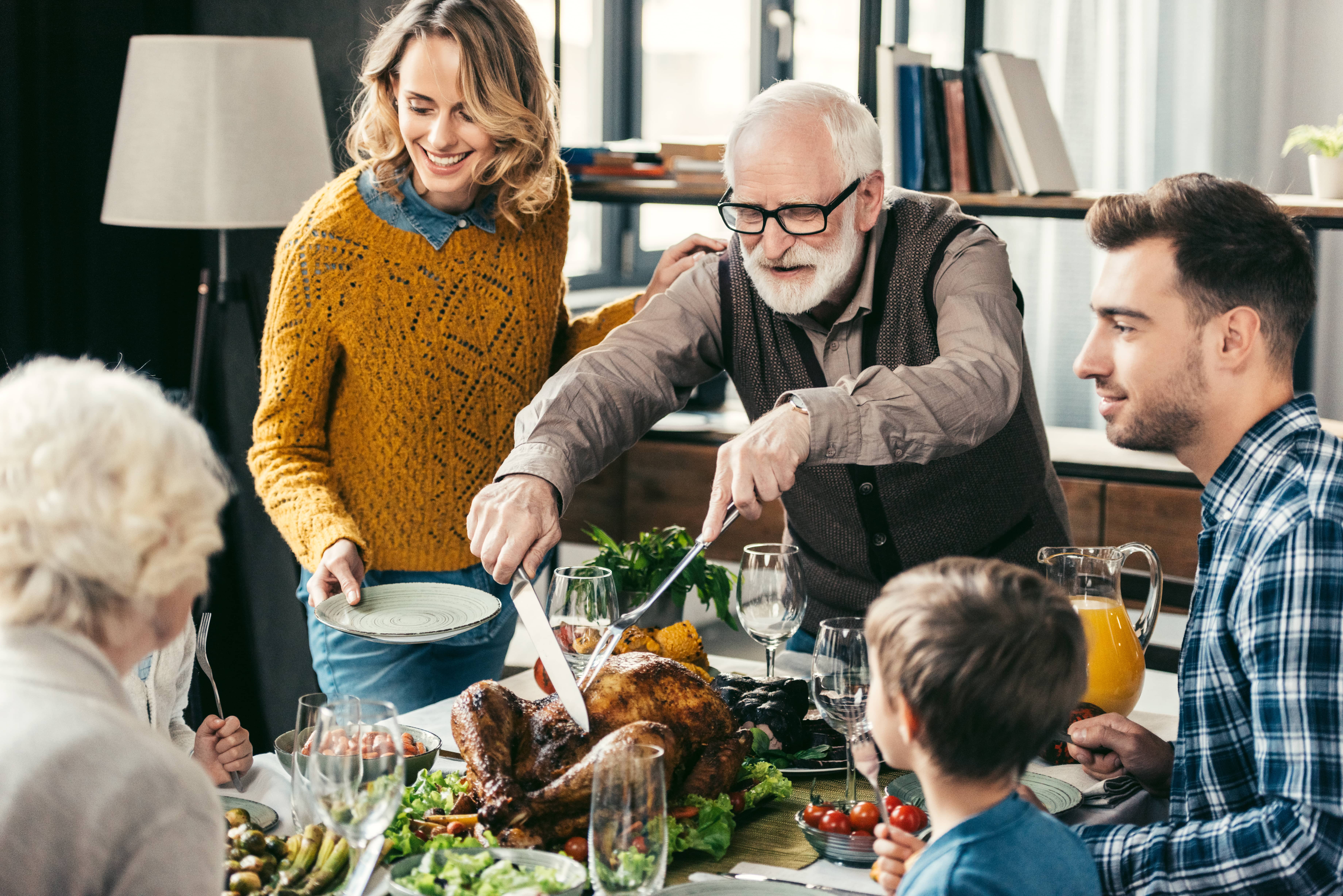 grandfather-cutting-turkey-for-family-on-thanksgiving-dinner