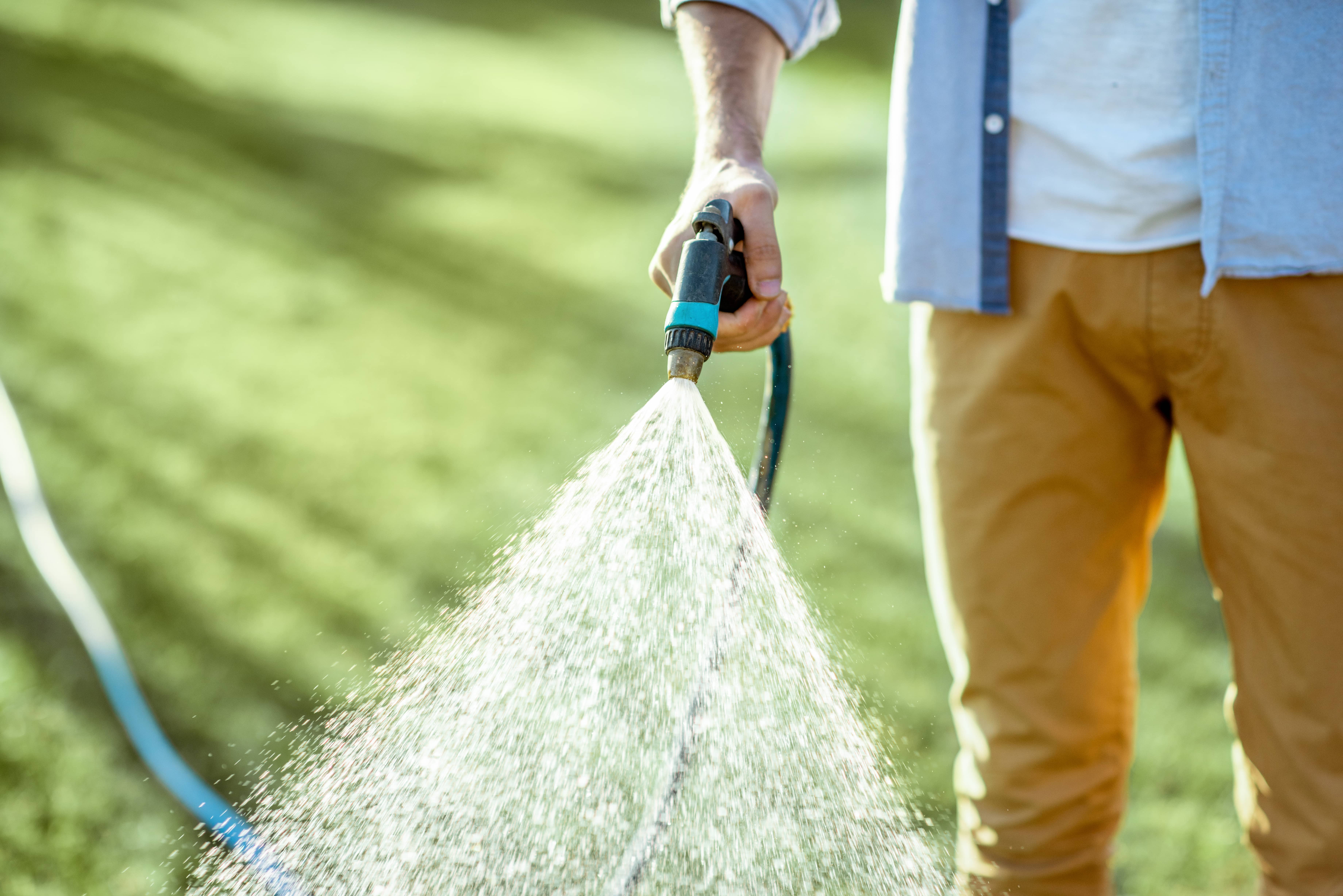 man-watering-green-lawn