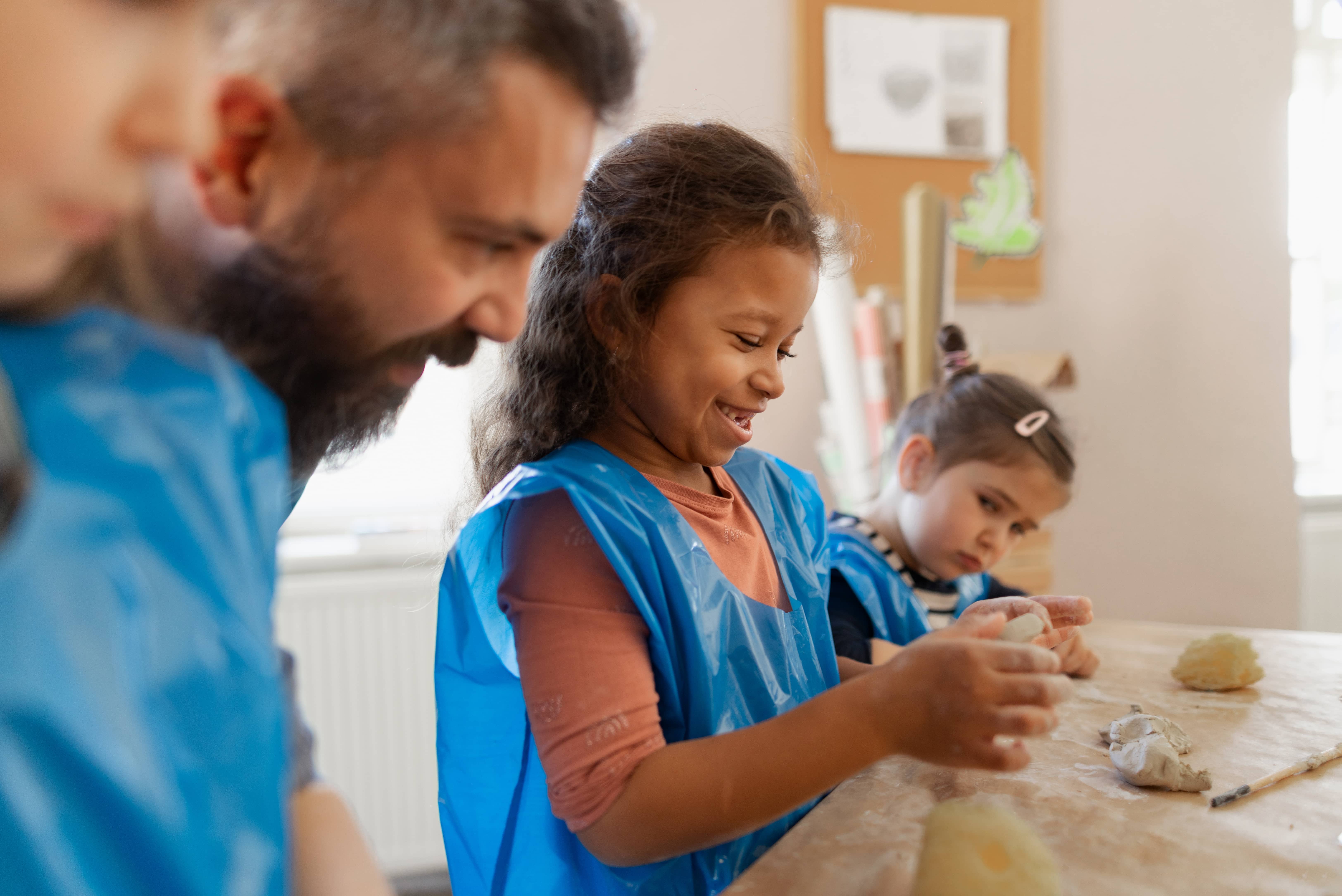 group-of-little-kids-with-teacher-working-with-pottery-clay-during-creative-art-and-craft-class-at-school