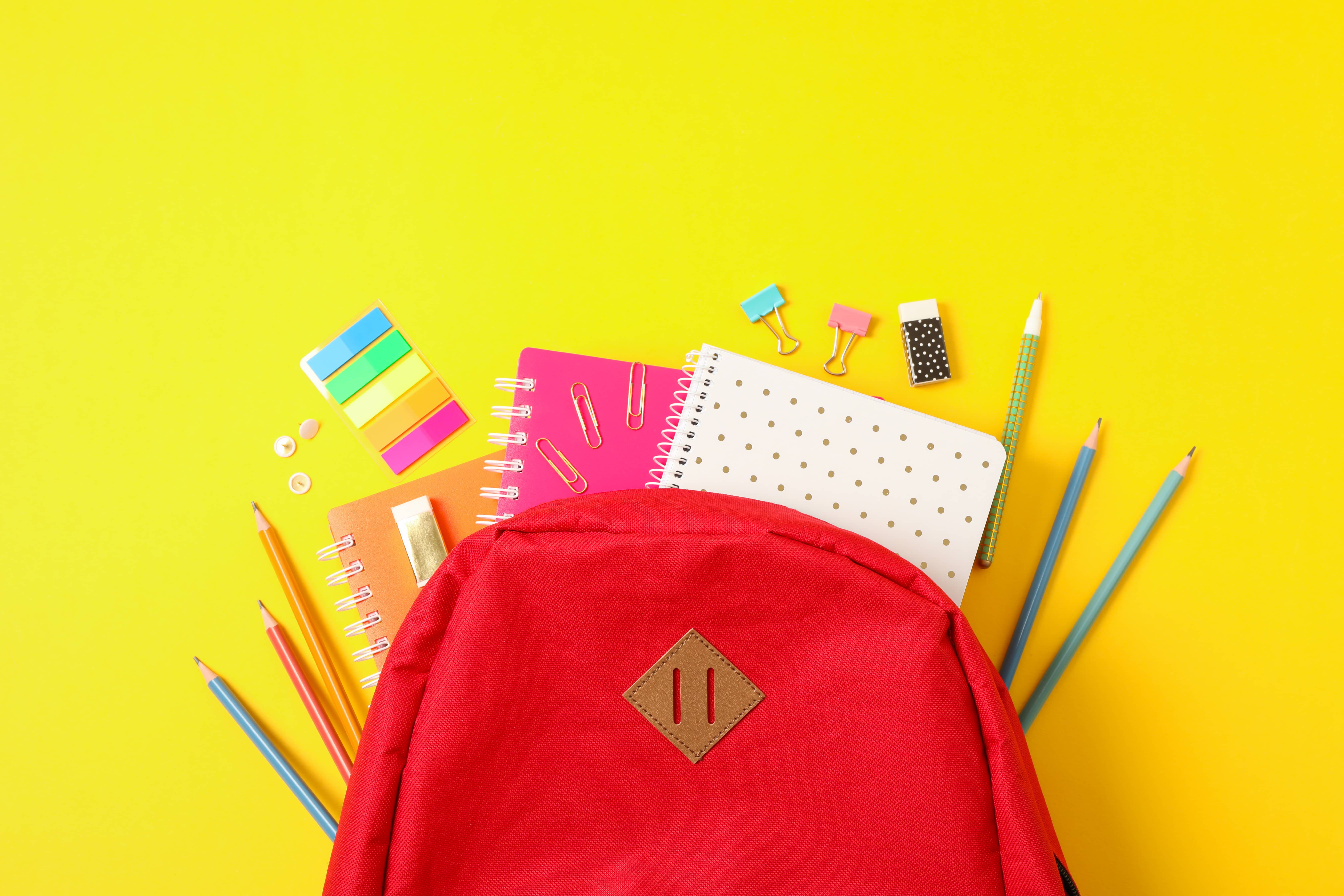 flat-lay-composition-with-backpack-and-school-supplies-on-color