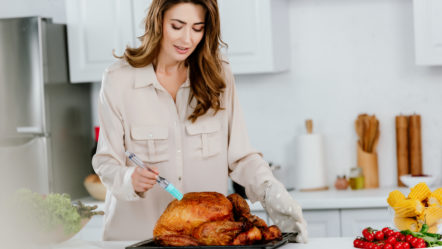 attractive-happy-woman-cooking-thanksgiving-turkey-at-kitchen