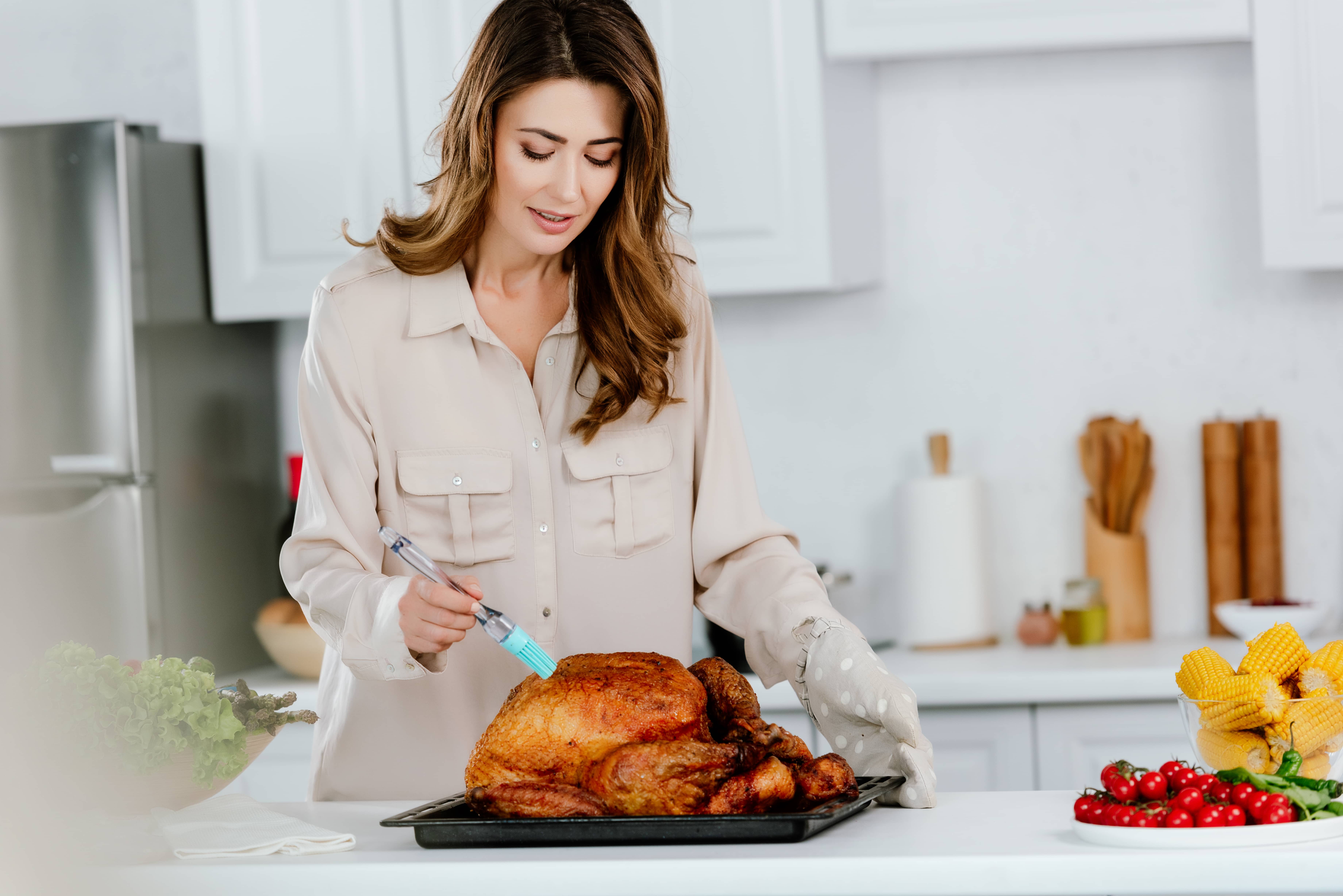 attractive-happy-woman-cooking-thanksgiving-turkey-at-kitchen