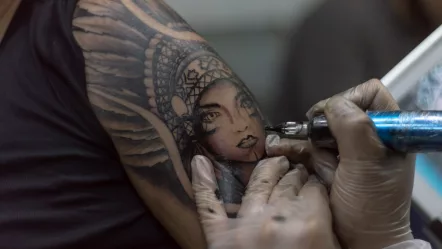 closeup-shot-tattoo-artist-holding-a-tattoo-machine-tattooing-a-person