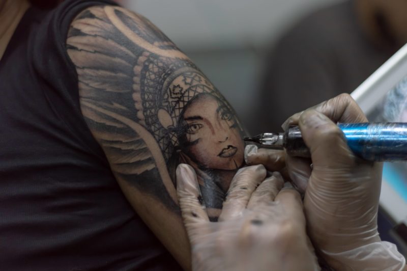 closeup-shot-tattoo-artist-holding-a-tattoo-machine-tattooing-a-person