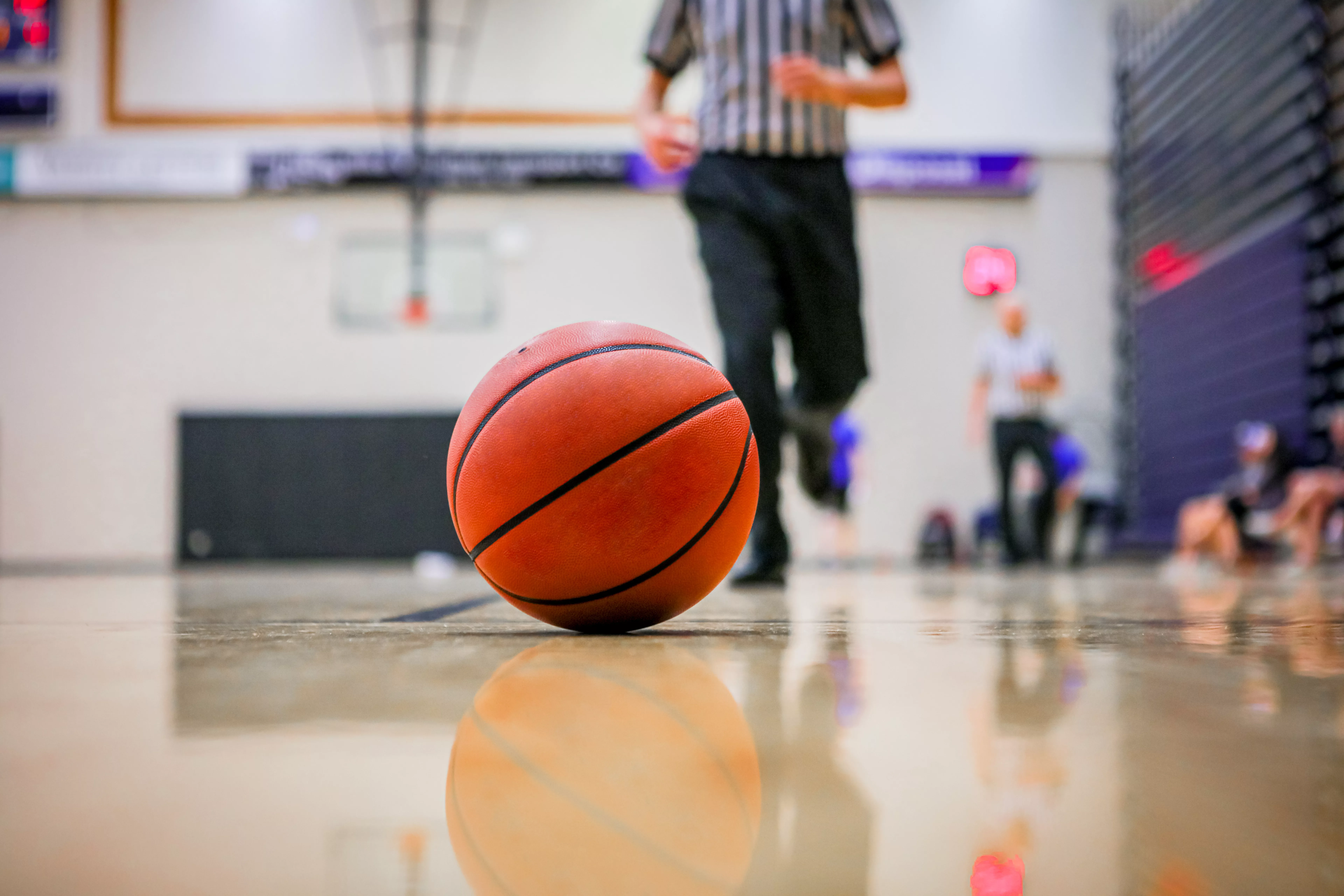 selective-focus-shot-of-a-basketball-rolling-in-the-hardcourt-referee