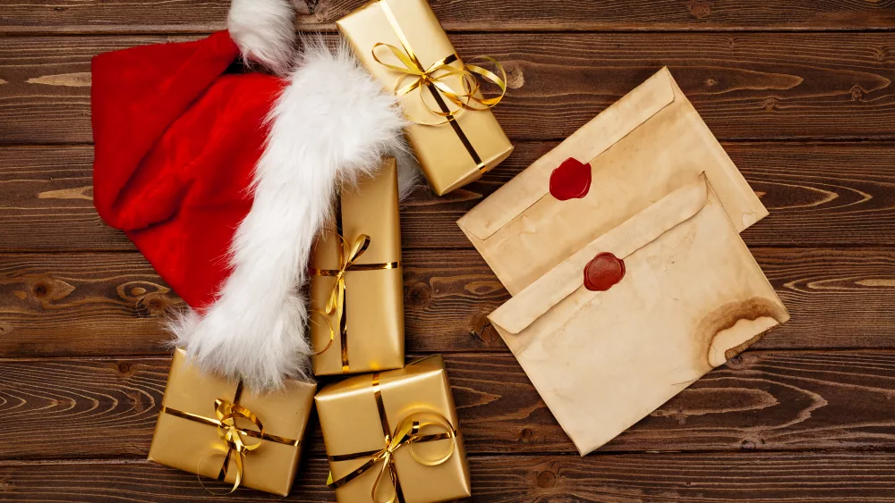 vintage-christmas-greeting-letter-and-wrapped-gift-boxes-on-wooden-background