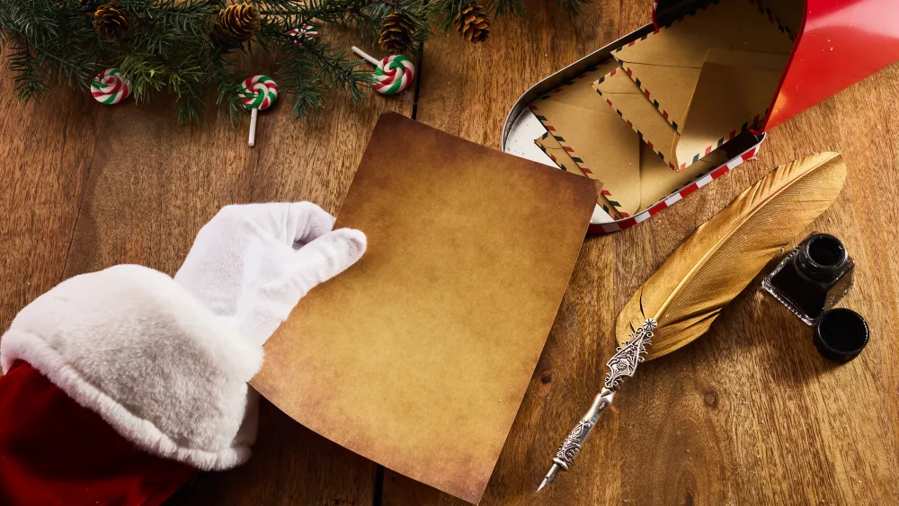 santa-claus-holding-an-empty-wish-list-in-his-hands-on-wooden-table