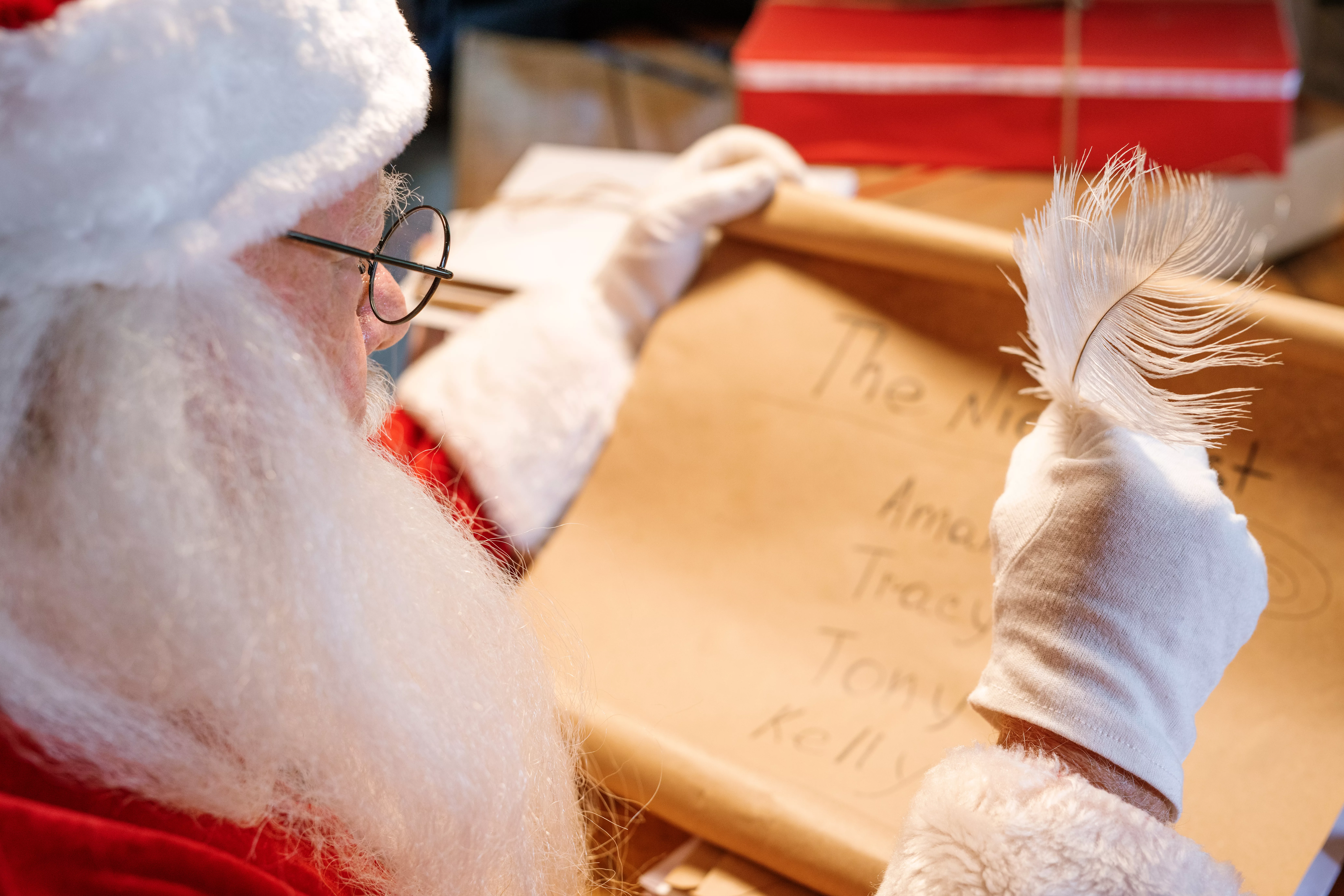 gloved-santa-claus-with-feather-in-hand-looking-through-nice-list