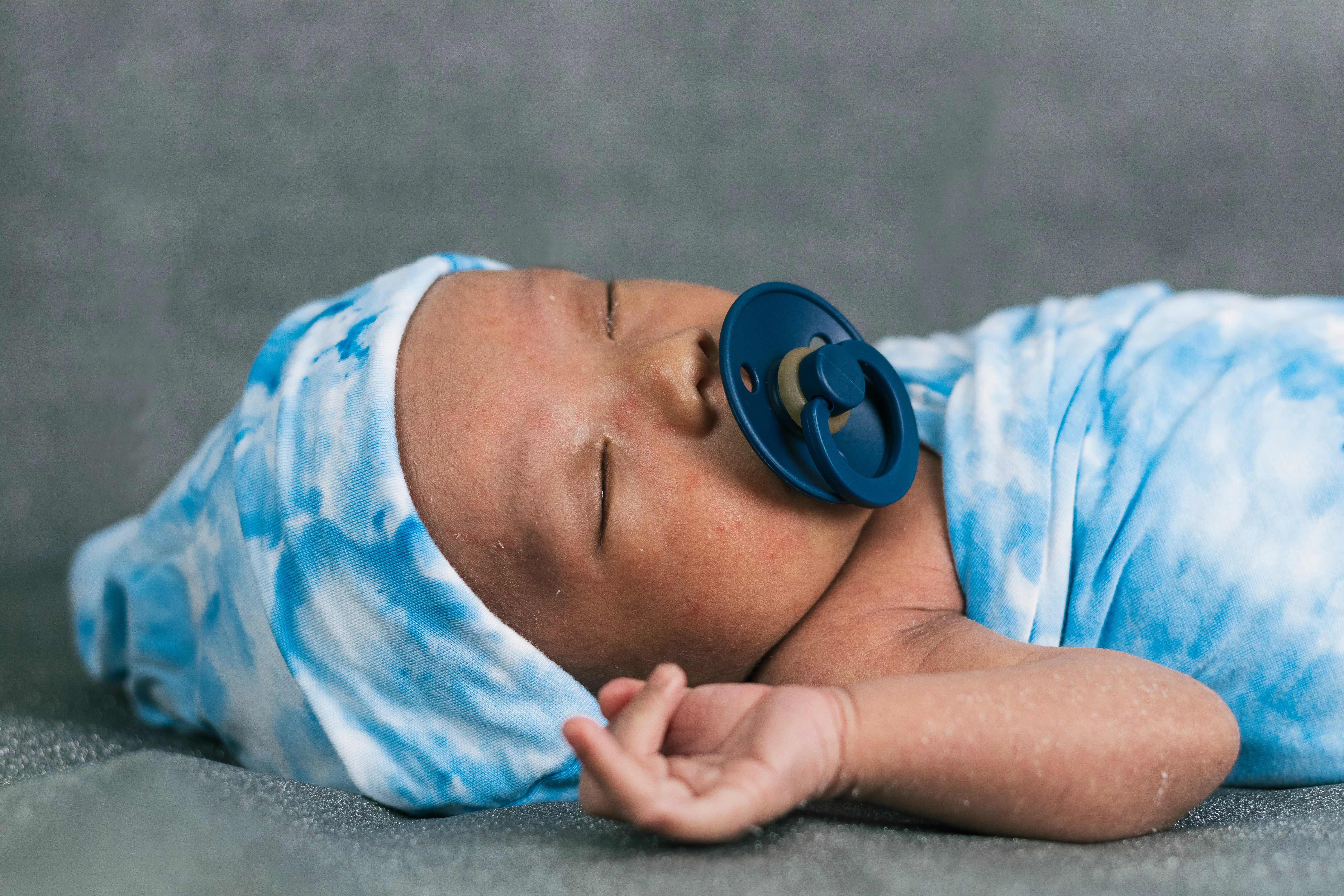 newborn-baby-wrapped-on-soft-blanket-with-pacifier