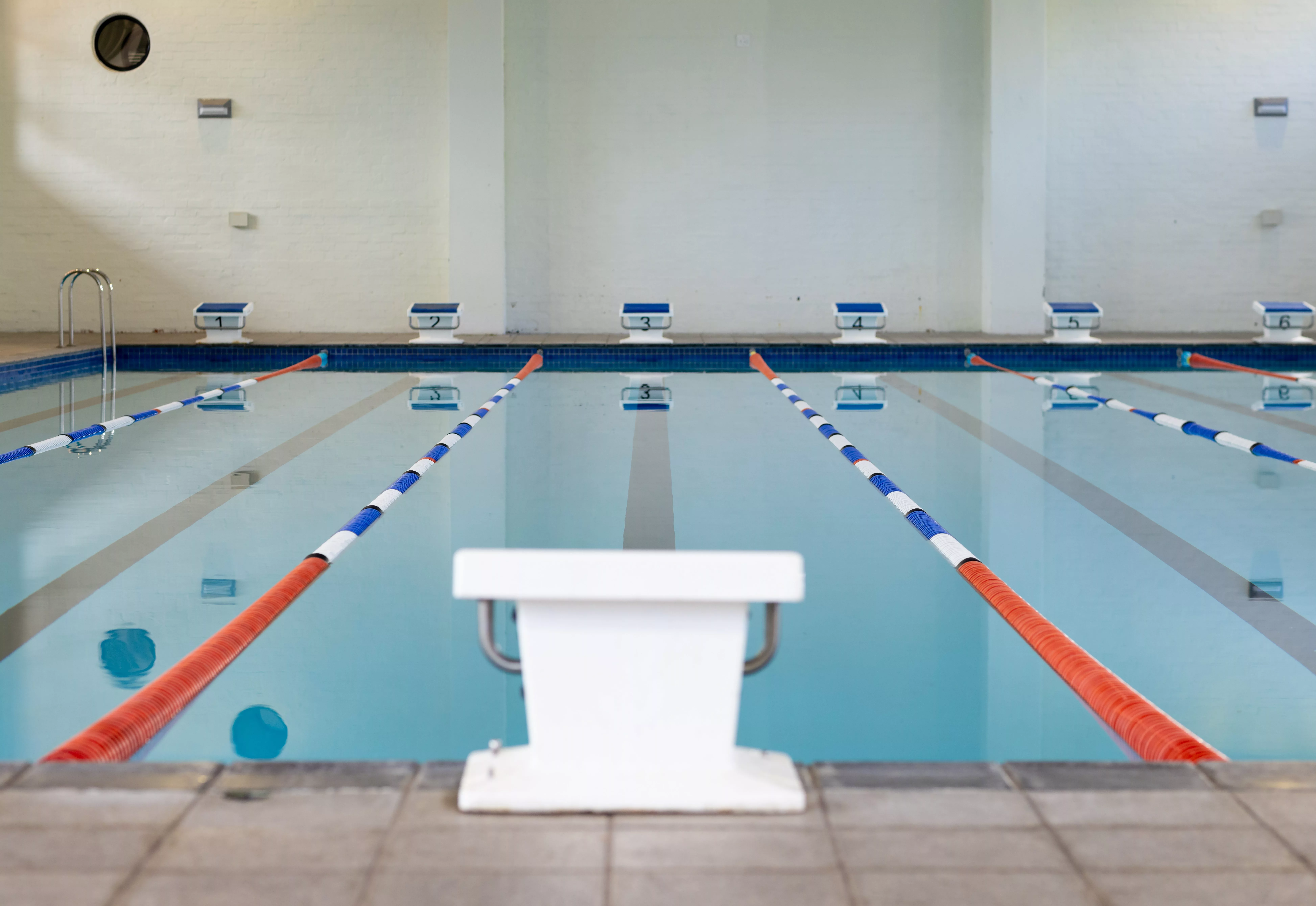 swimmers-are-not-present-in-the-indoor-pool-with-lanes-marked-for-racing-sunlight-filtering-through-windows-reflecting-on-calm-water-surface-unaltered