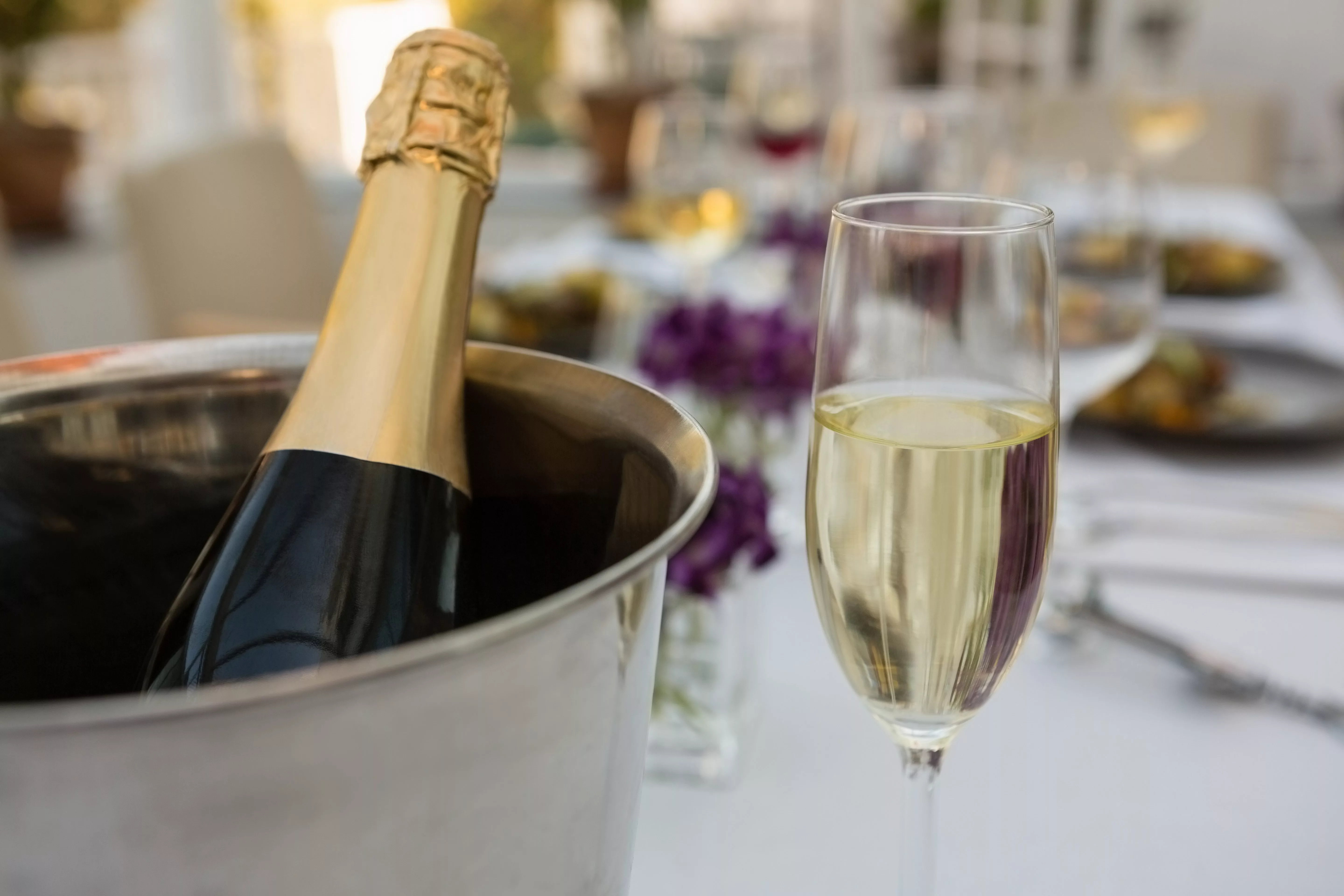 close-up-of-champagne-bottle-in-bucket-with-glass-on-table-in-restaurant