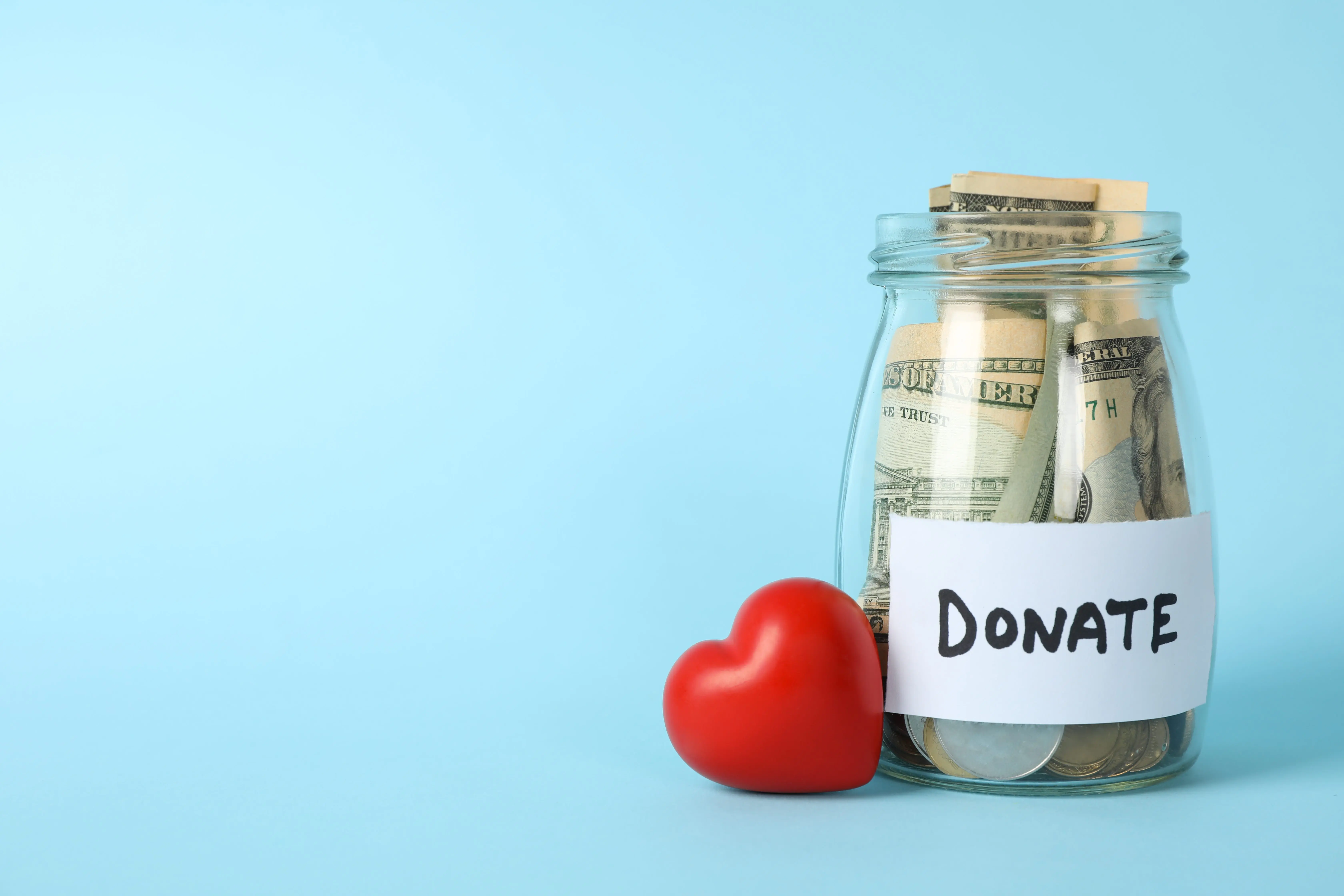 glass-jar-with-text-donate-and-heart-on-blue-background