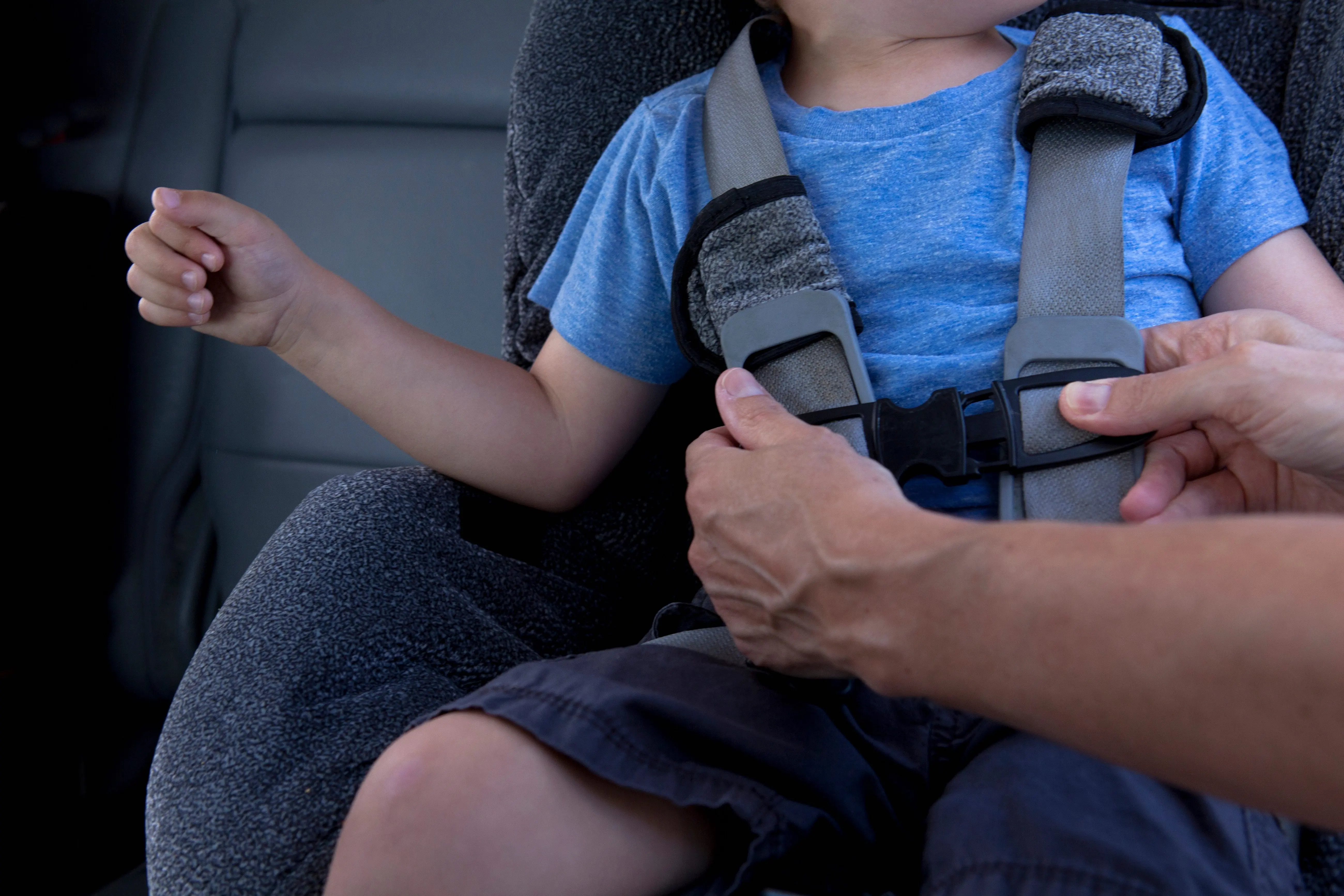mother-fastening-child-safety-seat-belt-in-car