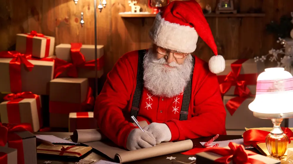 happy-santa-claus-working-on-christmas-eve-sitting-at-home-table