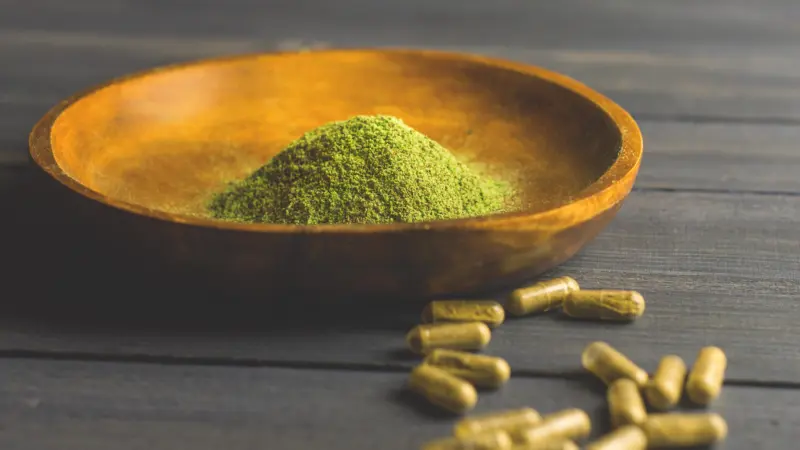 green-powder-and-capsules-on-wood-table-2026-01-07-02-23-21-utc