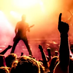 silhouette of guitar player in action on stage in front of concert crowd