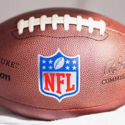 NFL Wilson Duke ball over a white sofa in a home. Sun light comes from a window.