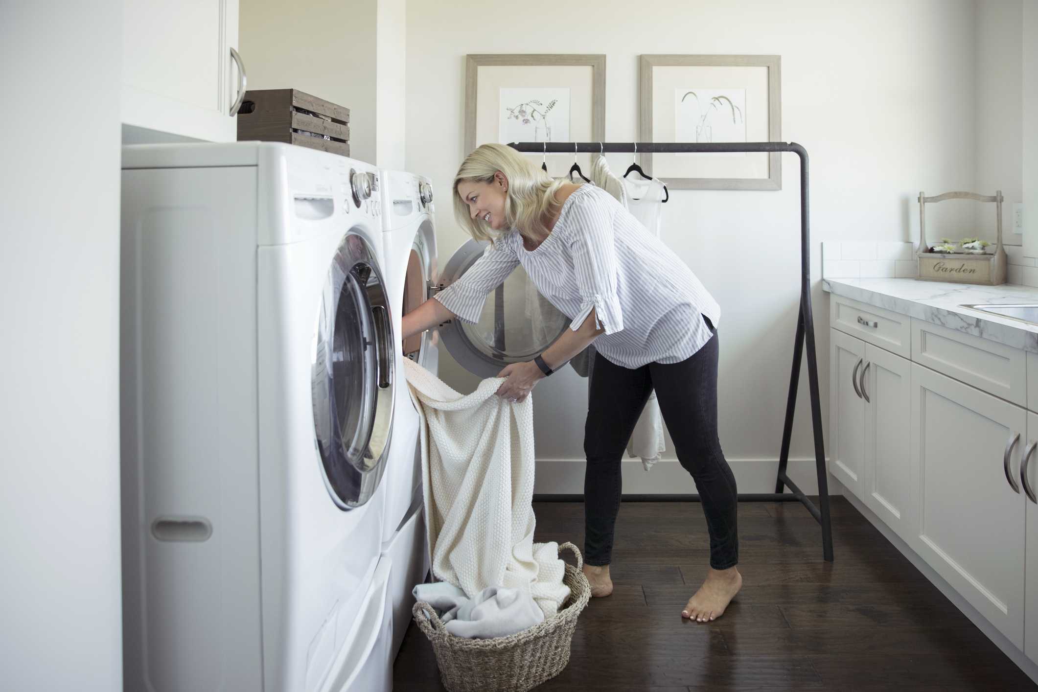 woman-removing-laundry-from-dryer-in-laundry-room-royalty-free-image-915093676-1556661060