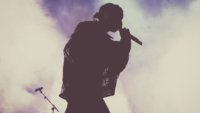 silhouette of rapper performing on stage with foggy background