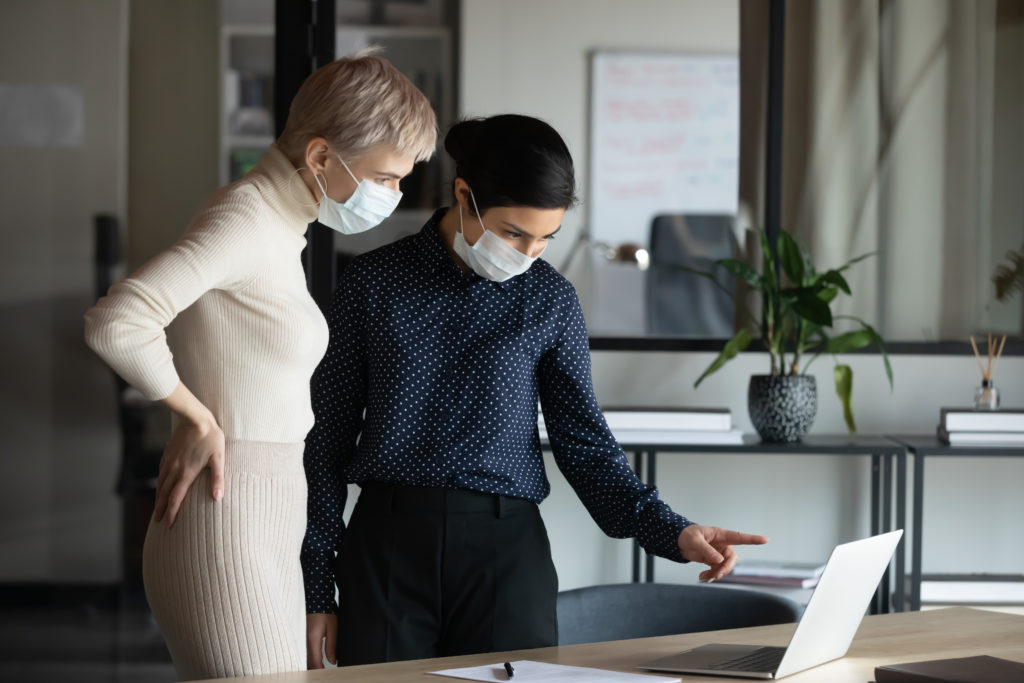 focused-two-women-in-medical-protective-masks-working-in-office