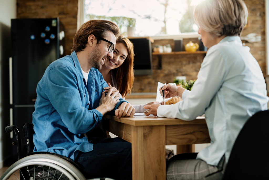 happy-man-in-wheelchair-and-his-wife-having-a-meeting-with-insurance-agent-at-home