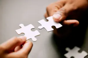 closeup-shot-of-two-unrecognizable-businesspeople-holding-puzzle-pieces-together