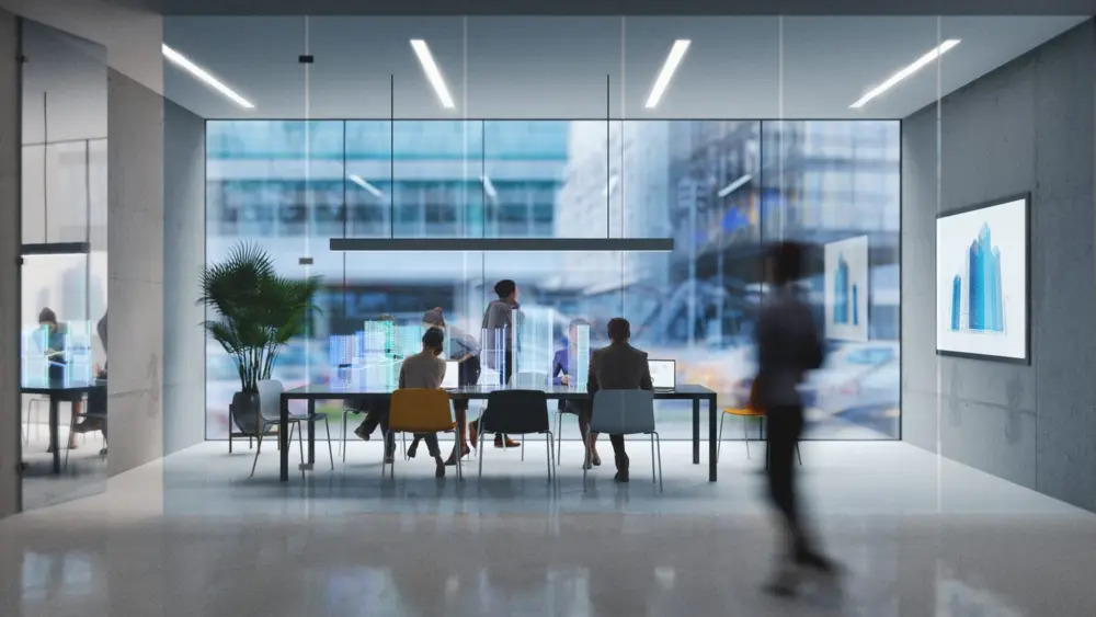 Group of people working in a modern board room or conference room with glass walls and people in hallway.