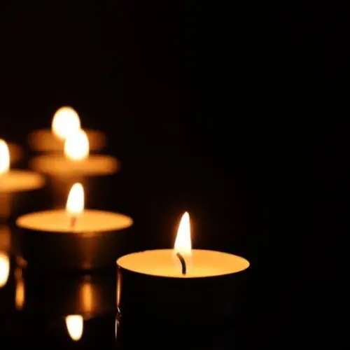 Burning candles on mirror surface in darkness^ closeup