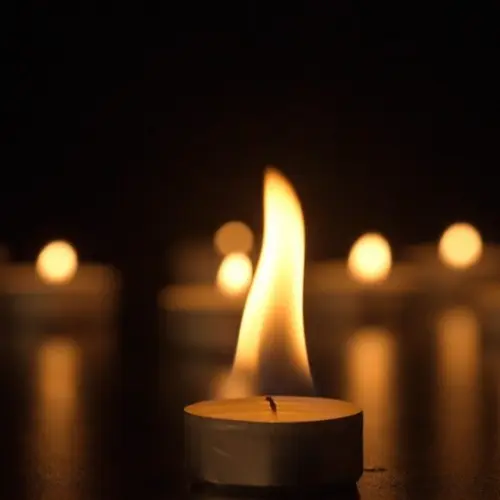 Burning candles. The candles burn against a black background and the flames move when the wind blows. The concept of a memorial day. Background for advertising and design projects.