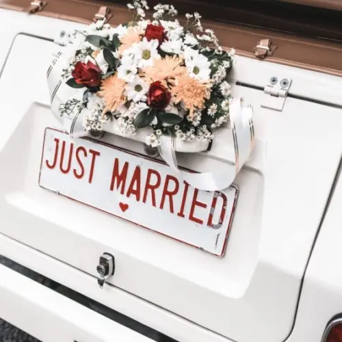 'JUST MARRIED" sign with flower decoration on white wedding car