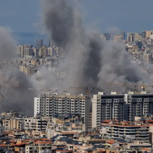 Multiple large plumes of thick grey smoke billow from residential apartment complexes following an explosion or missile strike in a crowded urban skyline. Jan 3 2021 in Iran
