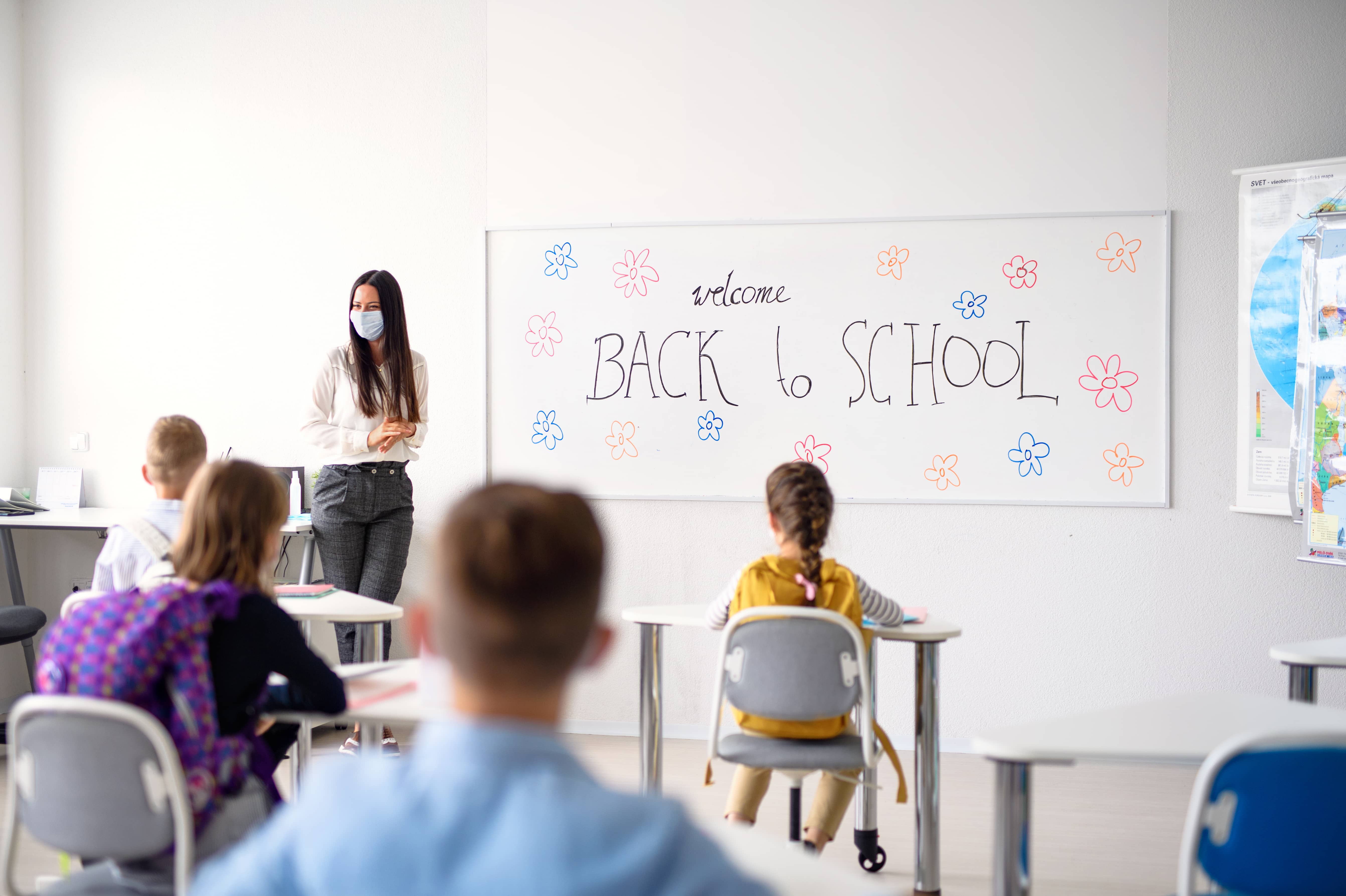 teacherwithfacemaskwelcomingchildrenbackatschoolafter