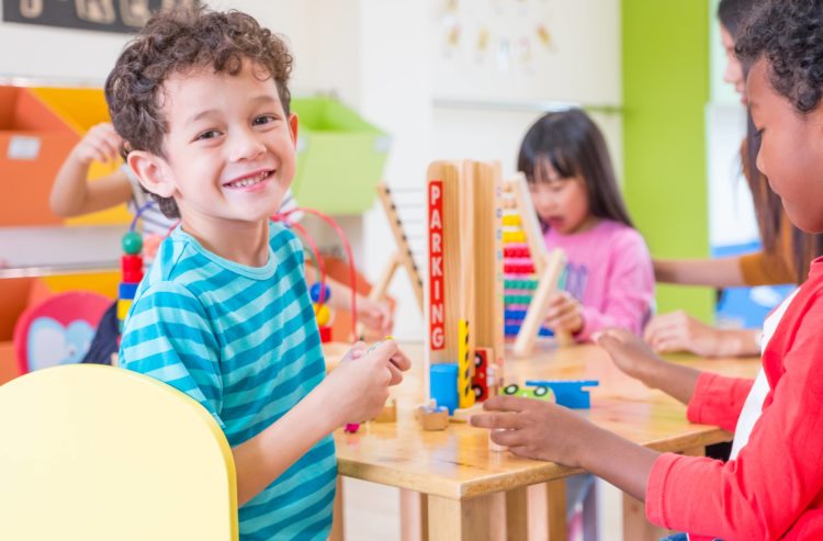 kindergartenstudentssmilewhenplayingtoyinplayroomatpreschool